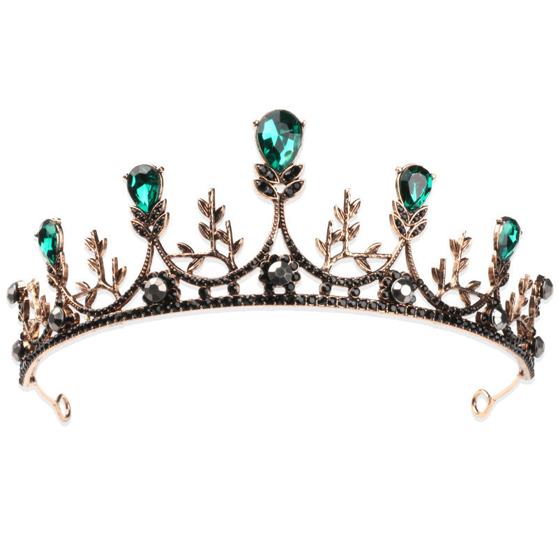 Vintage Baroque style crown with green gemstones and intricate leaf design.