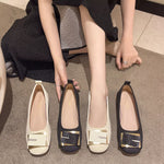 Round toe block heel slip-on shoes in black and beige with decorative buckle detail.