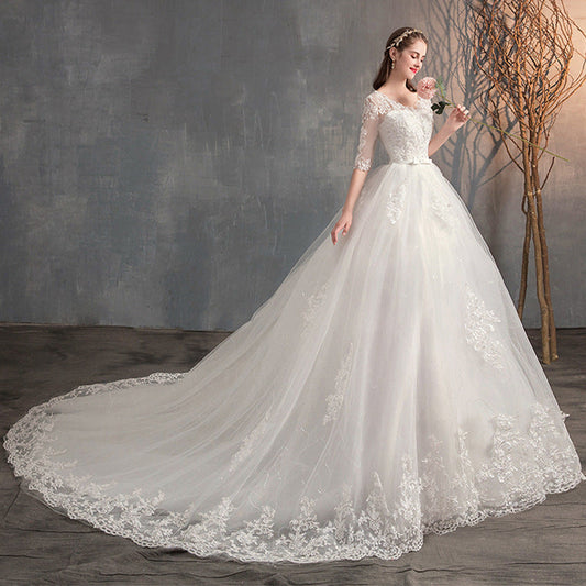 Wedding dress with long sleeves, deep V-neck, lace high waist, and trailing skirt.