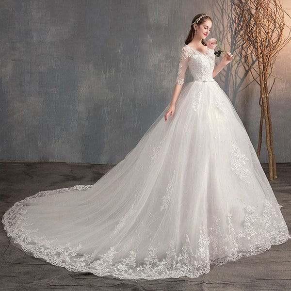 Wedding dress with long sleeves, deep V-neck, lace high waist, and trailing skirt.
