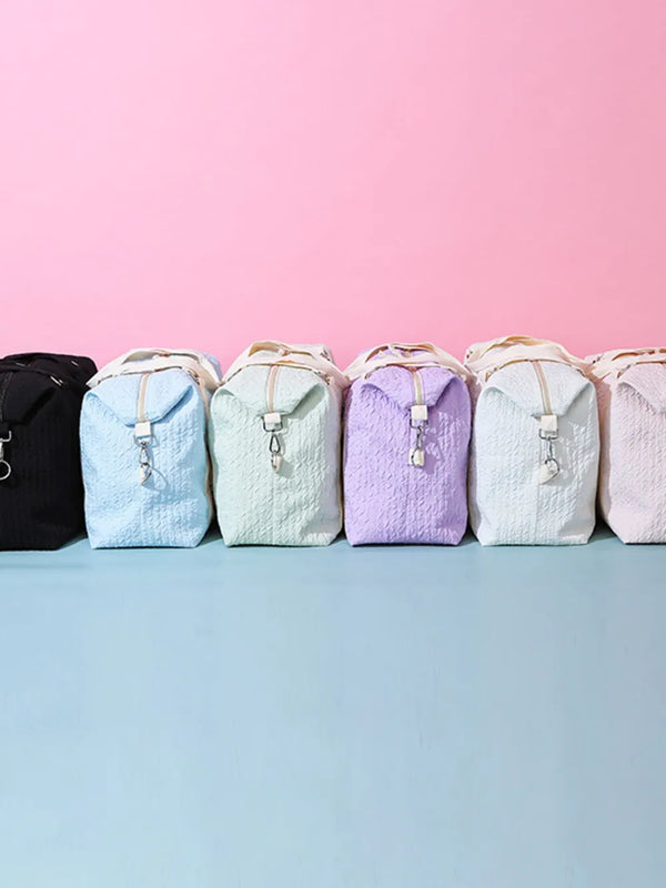 Large Texture Oxford Cloth travel bags in pastel colors with zipper and handle against pink background