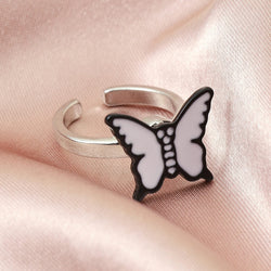 Unisex adjustable silver ring with white butterfly design on pink fabric.