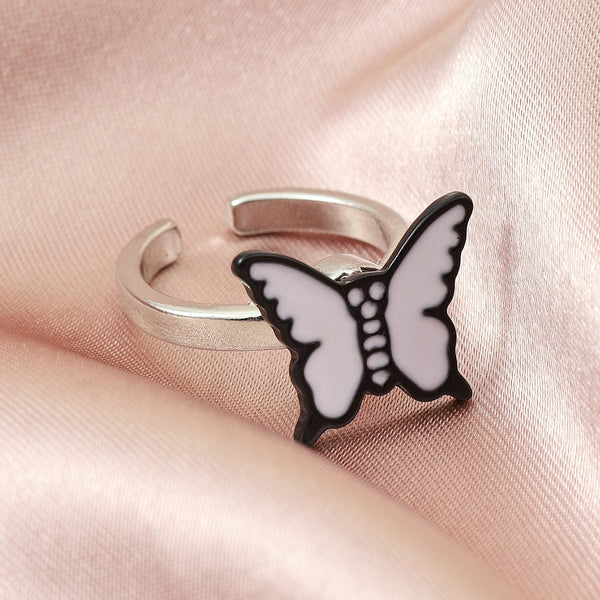 Unisex adjustable silver ring with white butterfly design on pink fabric.