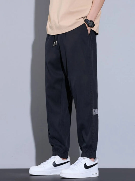 Men's plus size loose fit black jeans with drawstring and pockets, slightly stretchy polyester fabric.