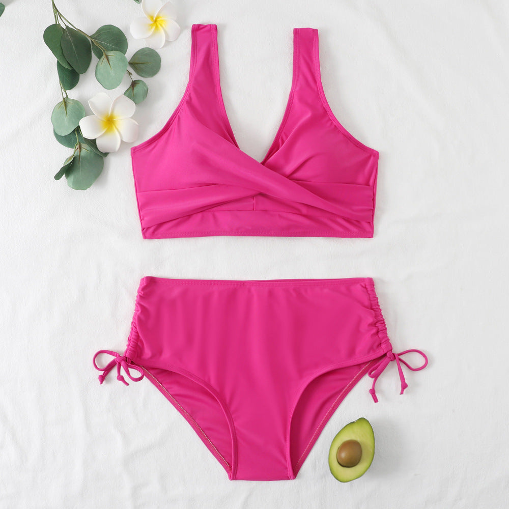 Rose red solid color cross bandage split bikini swimsuit on white background with floral decoration.