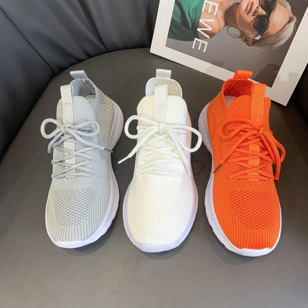 Women's fashionable mesh breathable running shoes in gray, milky white, and orange on display.