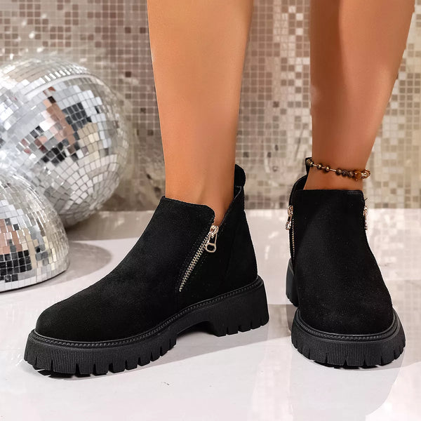 Black round toe side zip ankle boots with mid heels and rubber soles on model feet