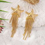 18K gold-plated starfish fringe drop earrings on sandy beach background