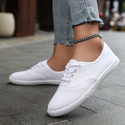 Women's white low-top running shoes with canvas upper and flat heel.