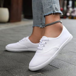 Women's white low-top running shoes with canvas upper and flat heel.