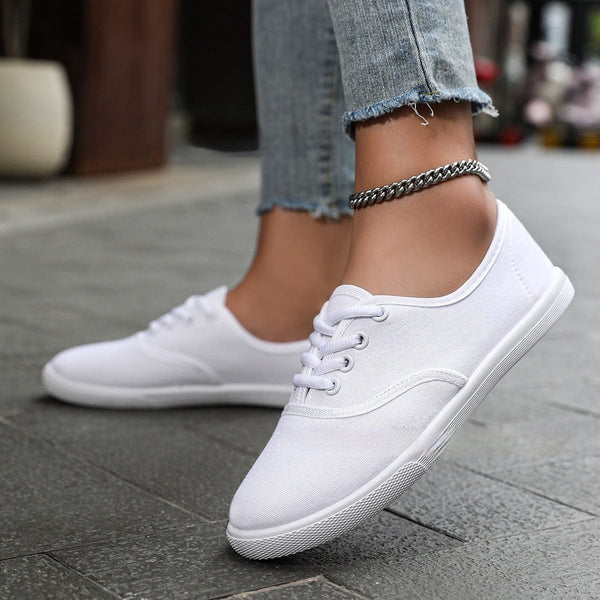 Women's white low-top running shoes with canvas upper and flat heel.