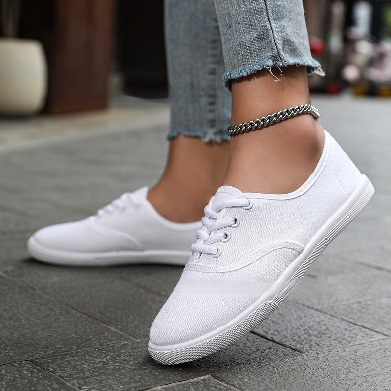 Women's white low-top running shoes with canvas upper and flat heel.