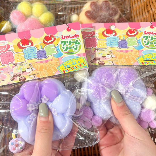 Large cat's paw squeezing toys in glossy and furry finishes in various colors, displayed in packaging.
