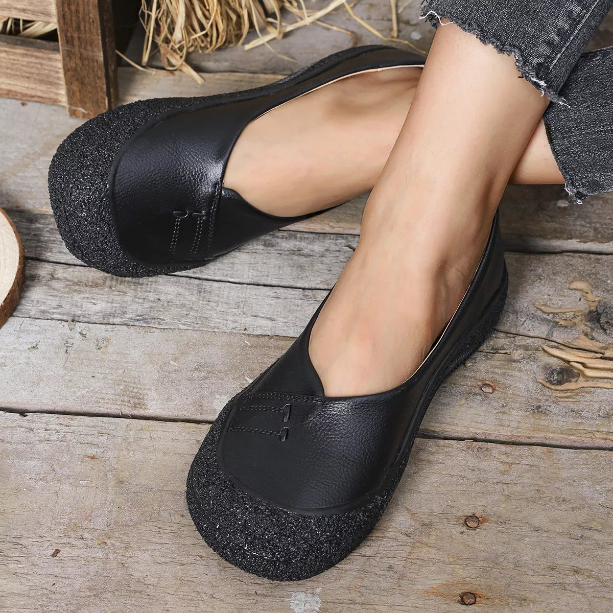 black PU leather round toe flats slip-ons with rubber soles worn with jeans on wooden floor