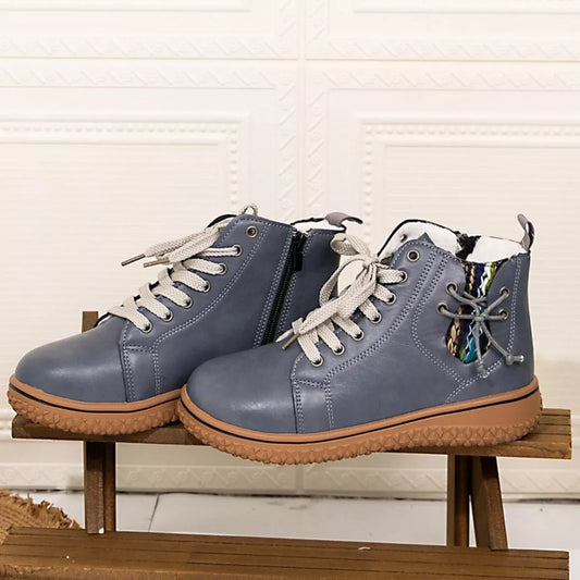 Blue round toe platform ankle boots with beige laces and rubber soles on wooden bench