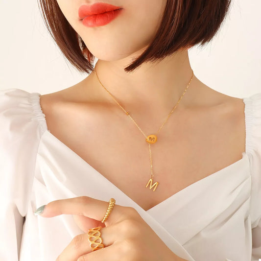 18K gold-plated titanium steel letter pendant necklace worn by woman with short hair and white top