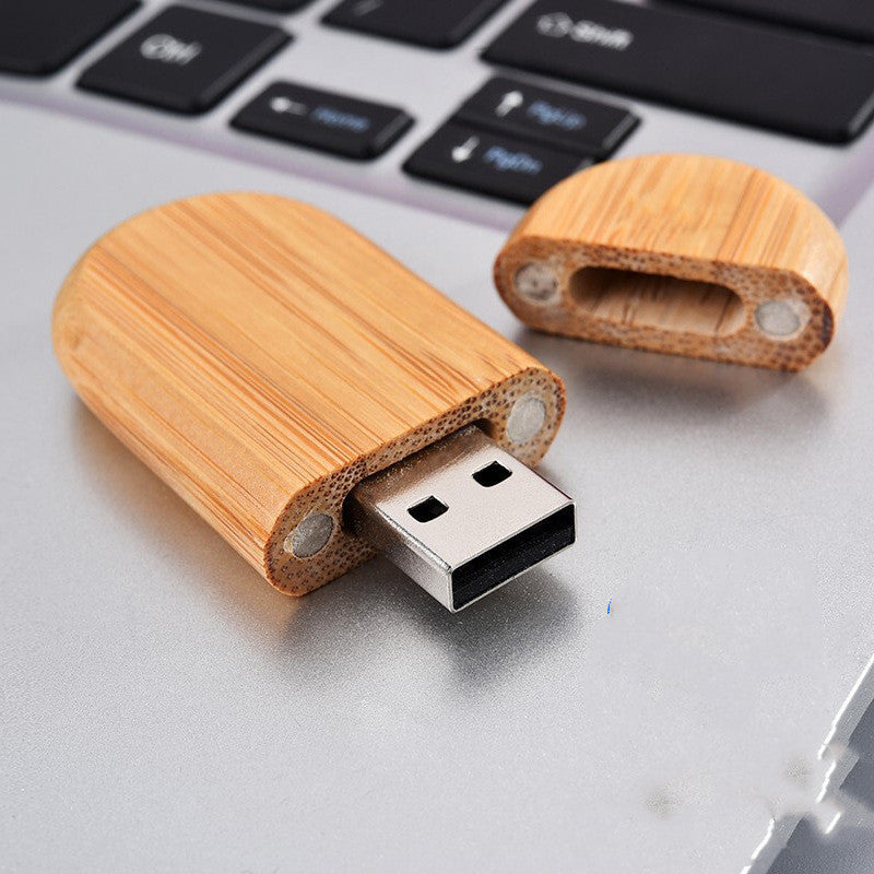 Wooden USB drive crafted from bamboo, open cap showing USB 2.0 interface, on a laptop.