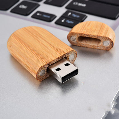 Wooden USB drive crafted from bamboo, open cap showing USB 2.0 interface, on a laptop.