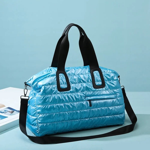 Light blue quilted nylon oversize travel bag with black handles and shoulder strap