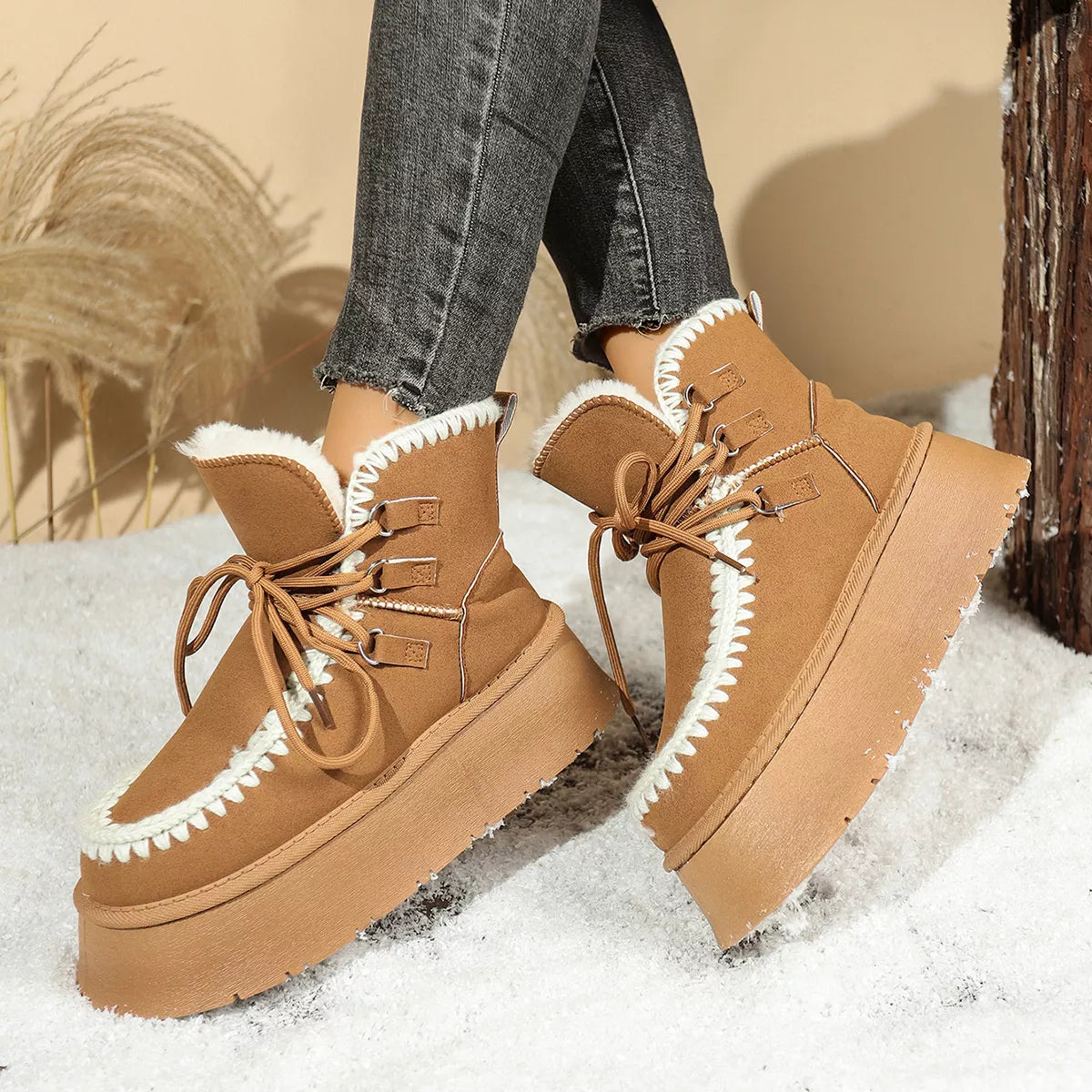 Brown sherpa lined platform snow boots with mid heel and lace-up design on snow background