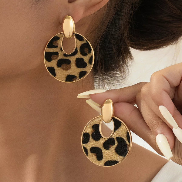 Leopard circle dangle earrings with 18K gold plating and alloy material worn on ear and held by hand