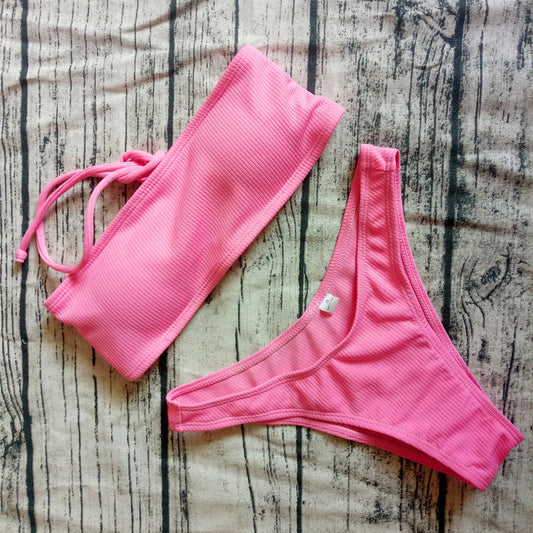 Women's solid color pink bikini set on wooden surface.