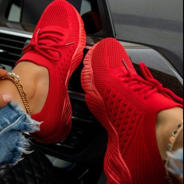 Red women's sneaker with thick bottom, sports style, in car interior.