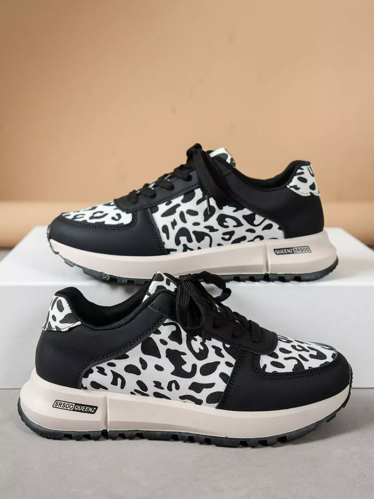 Pair of black and white round toe leopard sneakers with low heels and rubber soles