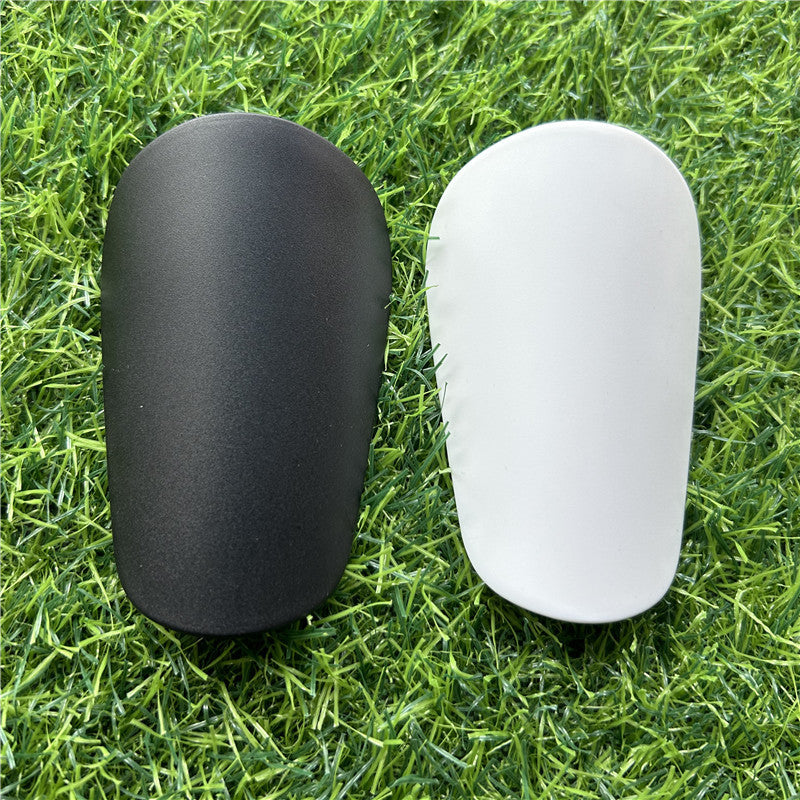 Extra small mini shin guards in black and white on grass.