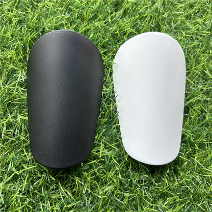 Extra small mini shin guards in black and white on grass.