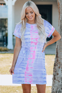 Woman wearing purple and pink tie-dye belted mini t-shirt dress with round neck and cuffed sleeves
