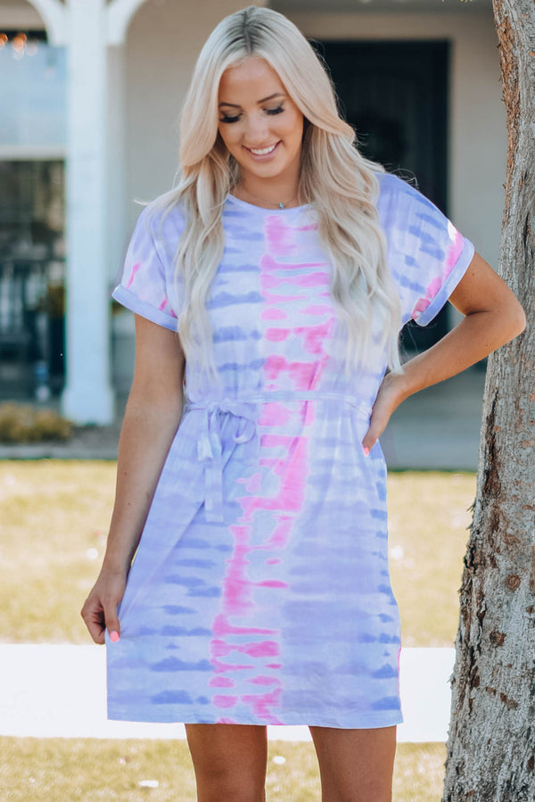 Woman wearing purple and pink tie-dye belted mini t-shirt dress with round neck and cuffed sleeves