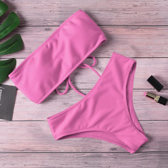 Ladies pink bikini one piece with sleeveless design on a wooden background.