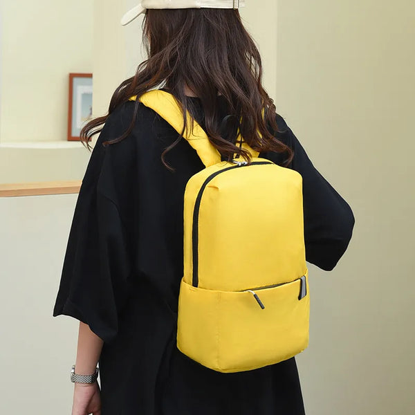 Solid color nylon backpack in yellow medium size worn by person
