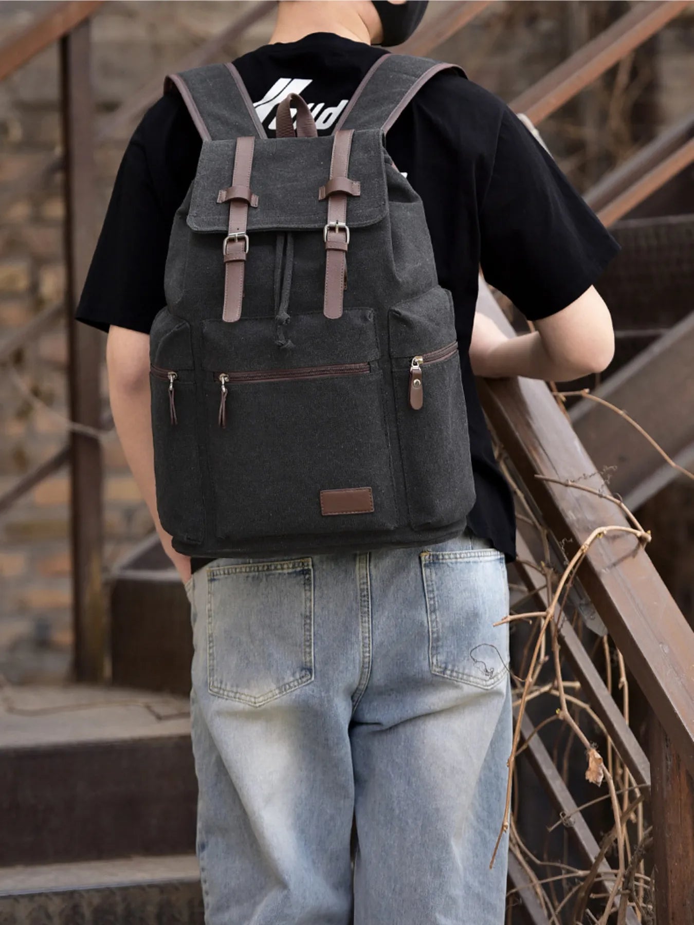 Large black canvas backpack bag with buckle straps worn by person