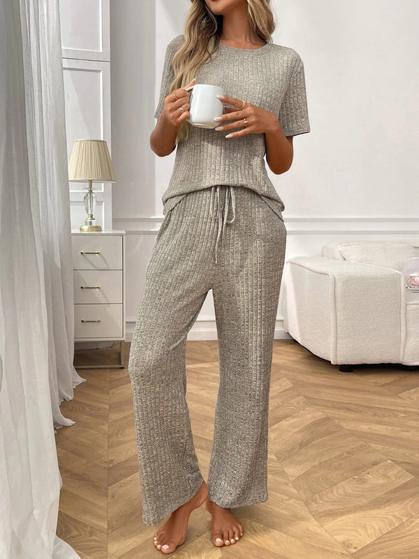 Woman wearing ribbed knit short sleeve top and pants lounge set holding white mug indoors