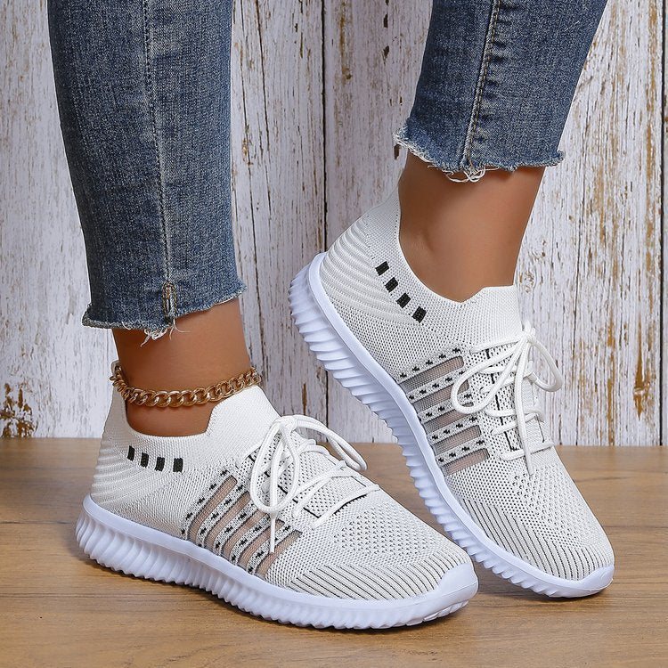 White women's flyknit wedge mesh casual shoes with lace-up design, worn with denim jeans, featuring low top and rubber sole.