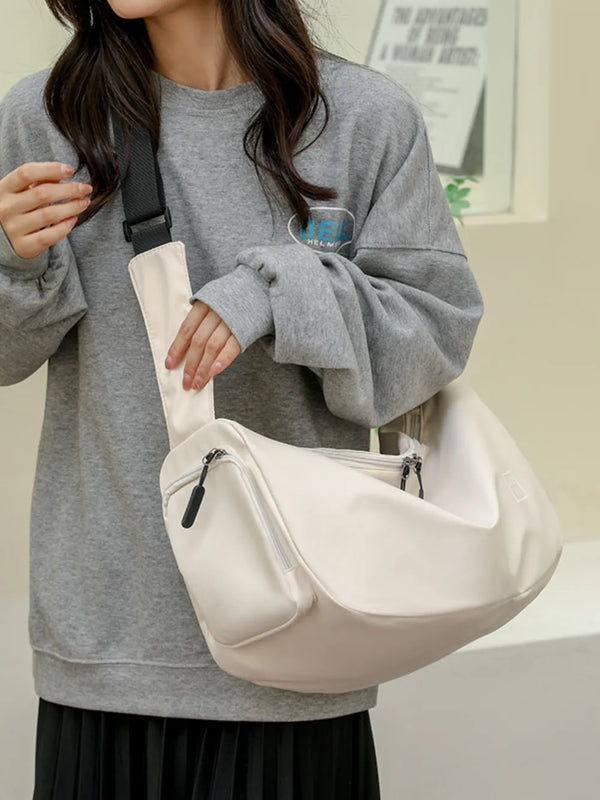 Large Oxford cloth crossbody bag in beige with multiple zippered compartments worn over shoulder
